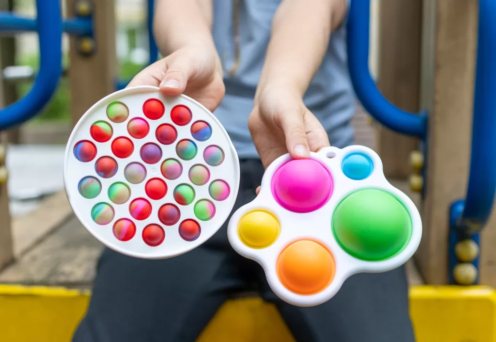colorful trendy antistress sensory toy fidget push pop it and simple dimple in kid's hands colorful trendy antistress sensory toy fidget push pop it and simple dimple in kid's hands