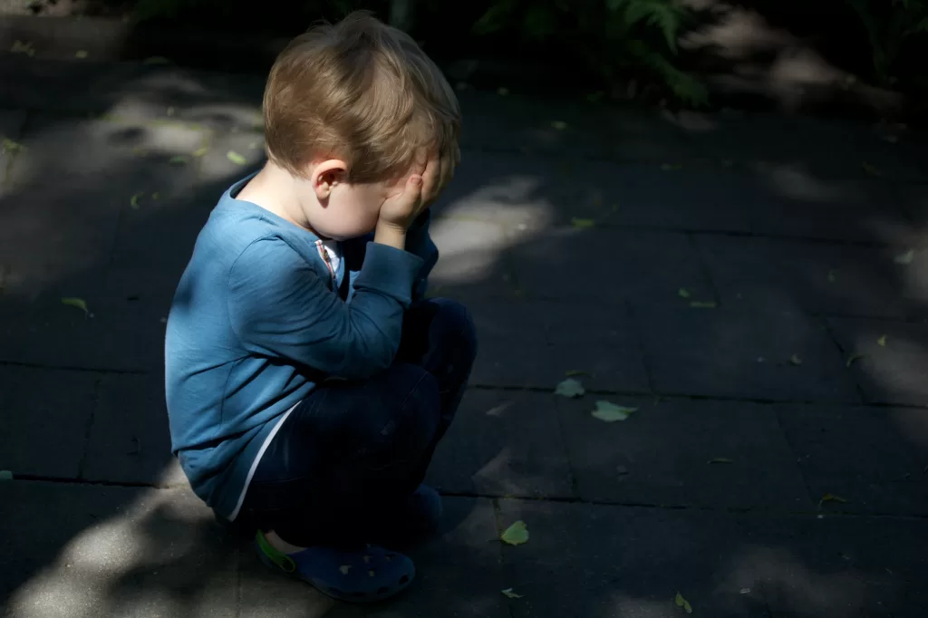 Autistic boy squatting in the street